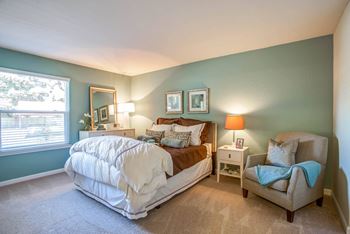 a bedroom with a bed and a chair and a window at Valley Plaza Villages, California